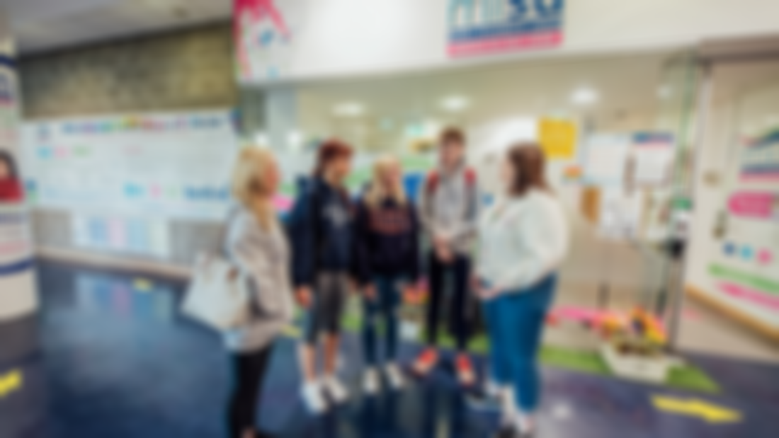 Four female and one male student are pictured chatting outside the MISU offices.