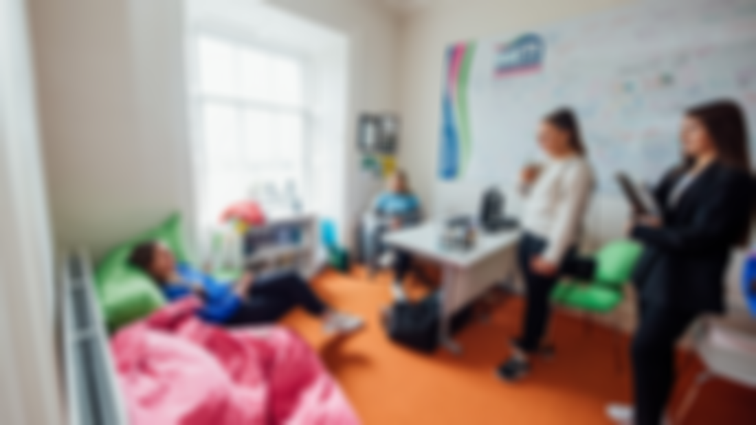 Four female students are pictured in a office with a desk and two large green and pink bean bags