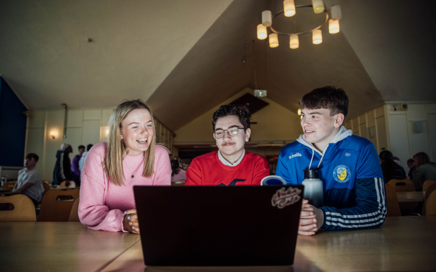 Three students looking at a laptop