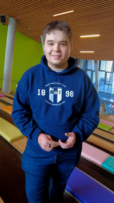 Male student standing at the top of the steps in the Tara building at MIC.