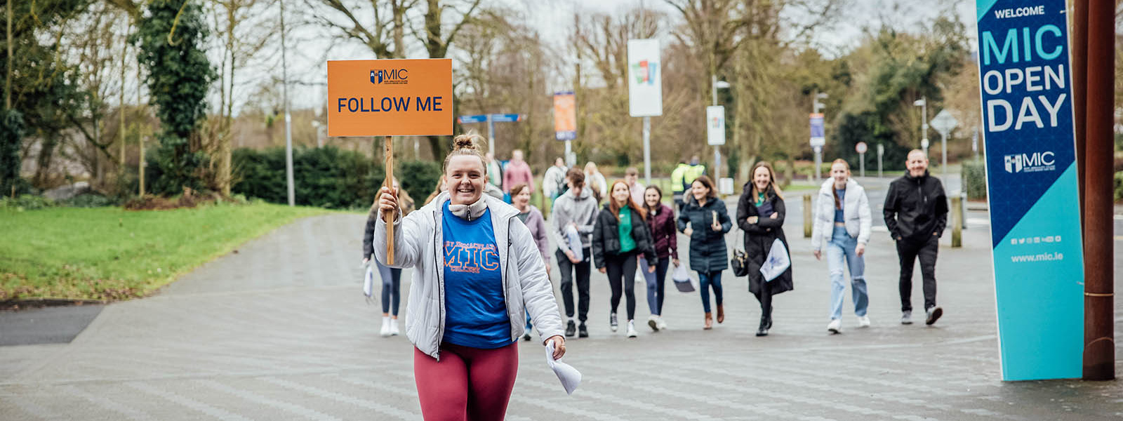 MIC student carrying a Follow Me sign leading a campus tour at college open day.