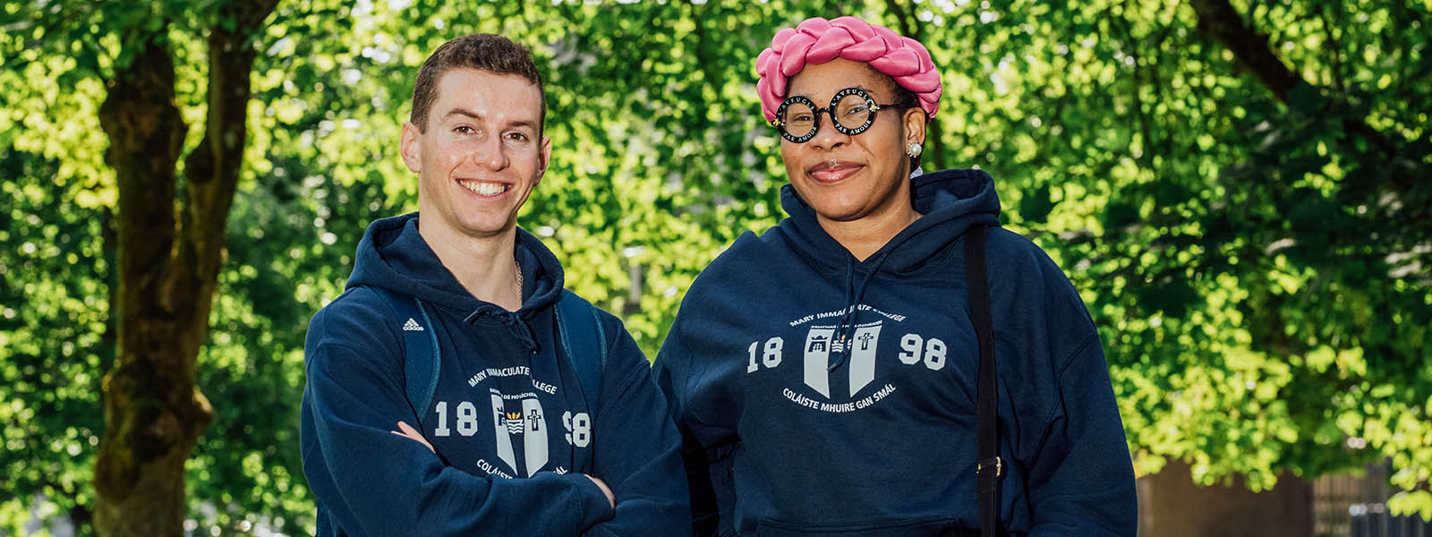 Two students wearing MIC branded hoodies on the grounds of MIC.