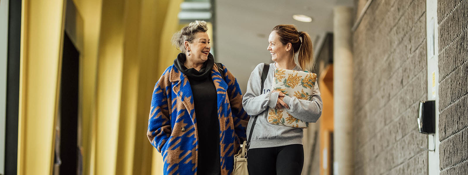 Two mature students walking in the hallway of the Tara building.