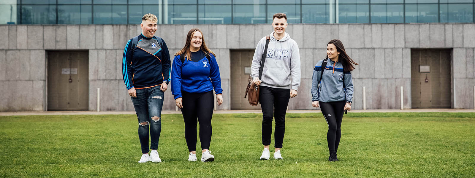 Four students wearing MIC branded hoodies on the grounds of MIC.