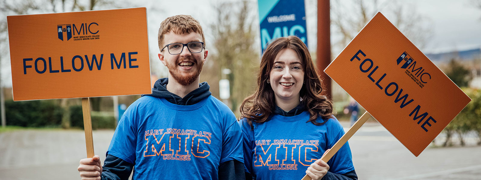 Male and female student carrying Follow Me signs leading a tour at MIC Limerick Campus.