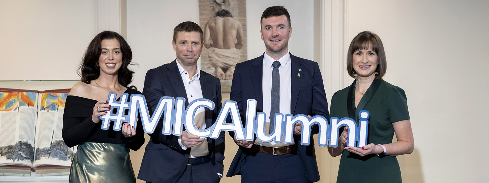 Four 2023 MIC Alumni of the Year Awardees holding a #MICAlumni sign.