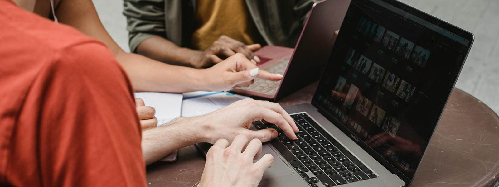Cropped image of students sitting at a table with laptops open