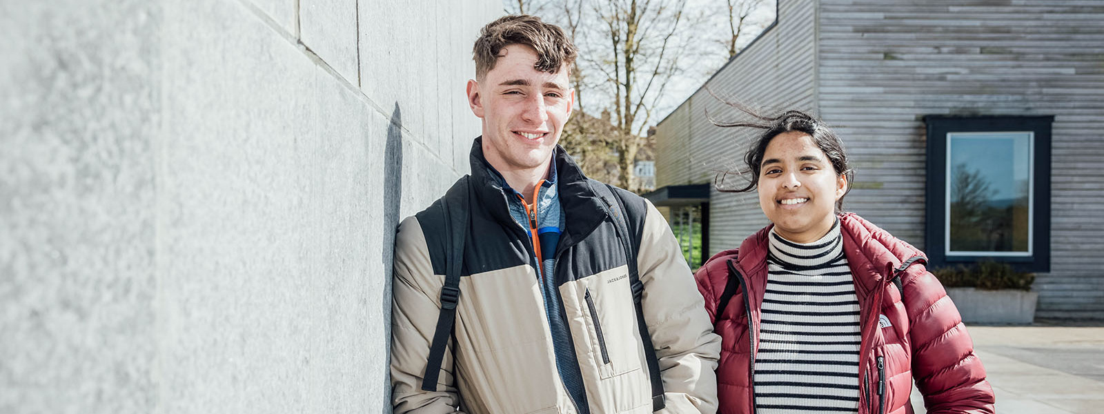 Male and female students standing at the side of Tailteann building in MIC