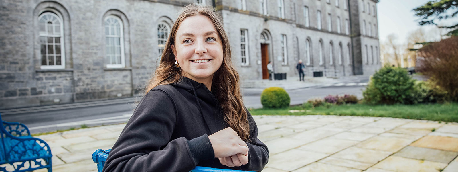 Undergraduate student sitting on a bench outside the main building at MIC Thurles.