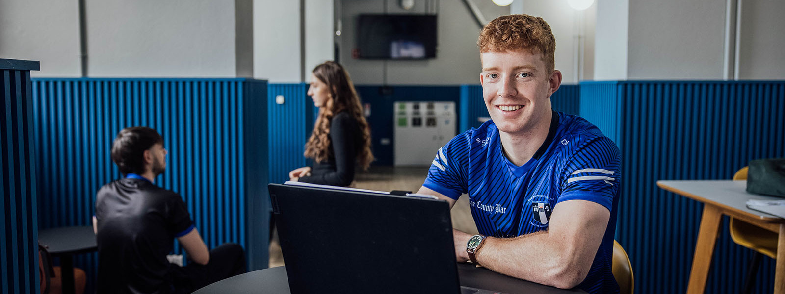 Undergraduate students sitting at a table with an open laptop in the student lounge at MIC Thurles.