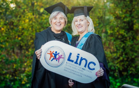 2 LINC programme graduates holding LINC sign for Graduation 2019