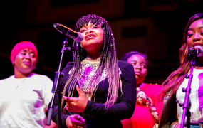 A woman stands at a microphone singing 