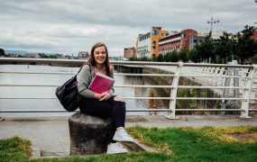 Female student sitting with the River Shannon in the background 