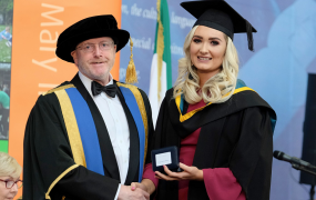 Louise Curtin pictured in her graduation gowns being presented with a medal from Professor Eugene Wall, President of MIC