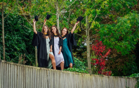 Three MIC students wave to camera