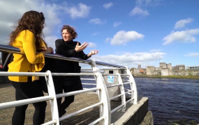 Two women talk at railings beside the River Shannon in Limerick
