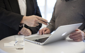 stock photo of two men around a laptop with one pointing to something on screen