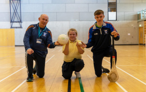 Dr Richard Bowles, Ava Kiely and David Geary holding a football and hurley at the launch of the Centre of Excellence