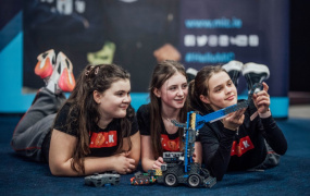 Three female students looking at a robot