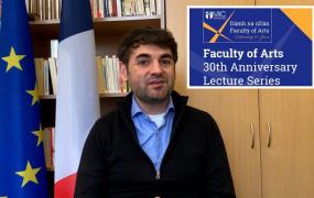 Dr Loic Guyon sitting in front of a French and European Union flag