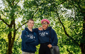 Male and female student standing in front of trees at MIC