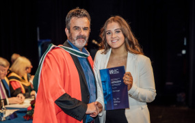 Male academic handing female academic award on stage