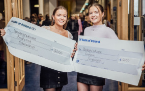 Twins Niamh and Tara Ryan holding prop cheques at the College Awards ceremony