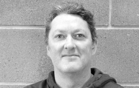 Dr Brian Desmond in black and white in front of a cement wall