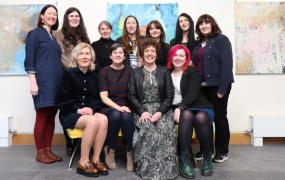 FemFest committee group photo. Four women seated in front and seven women standing behind.