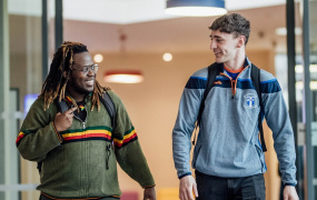 Two male students walking through door and talking to each other