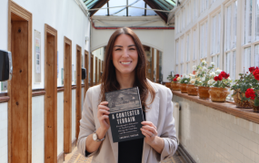 AnneMarie Brosnan holding a copy of her published book, A Contested Terrain