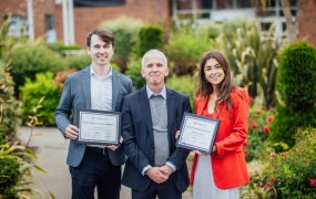 Two teaching fellows with the president of a college posing for a picture with their teaching excellence award