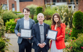 Two teaching fellows with the president of a college posing for a picture with their teaching excellence award