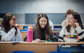 Three newly qualified teachers sitting in a lecture room for a conference