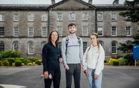 Three students standing outside their college campus