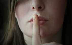 A closeup of a woman ssshing (be quiet)