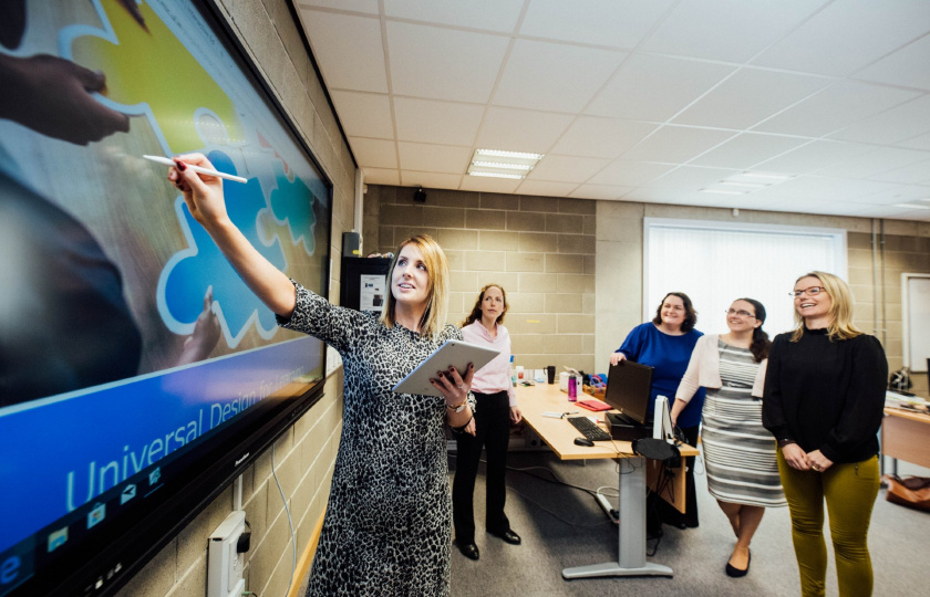 Students standing around a whiteboard in an MIC classroom