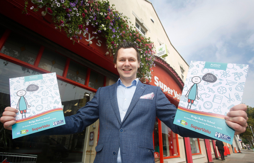 Image of AsIAm CEO Adam Harris holding the new resource outside a Supervalu shop