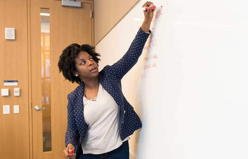 Teacher writing on white board with red marker