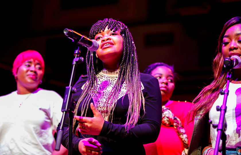 A woman stands at a microphone singing 