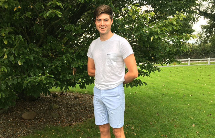 Keith O Riain pictured outside by a tree wearing a white t-shirt and blue shorts 