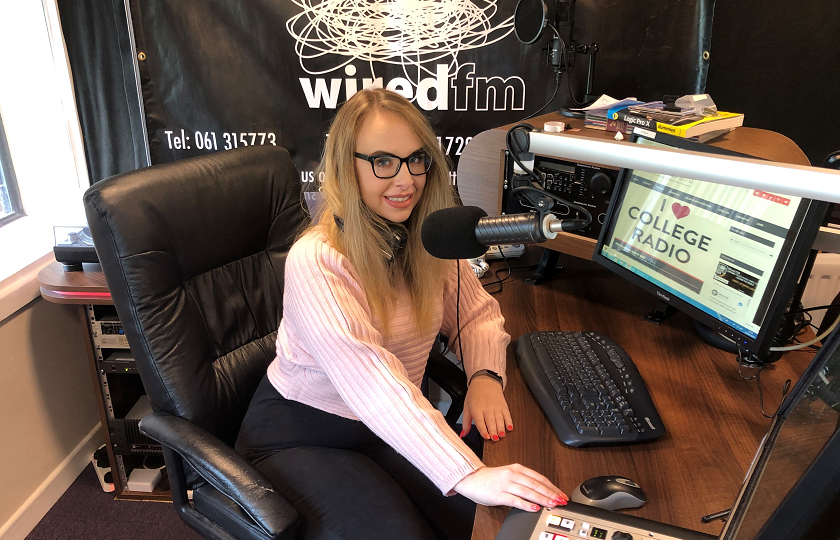 MIC student, Vanessa Flood, pictured sitting at the mic in the Wired FM radio studio