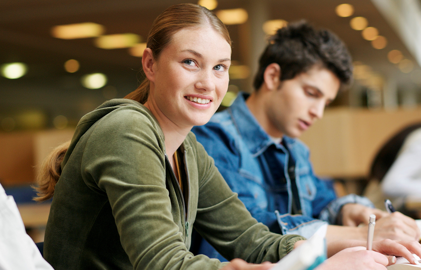 Woman and man sitting in a library studying 