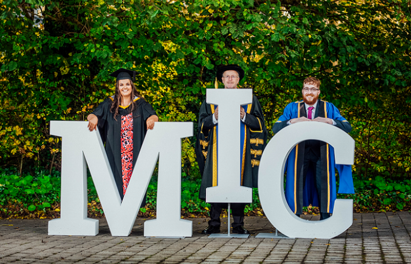 Graduating students behind an MIC sign