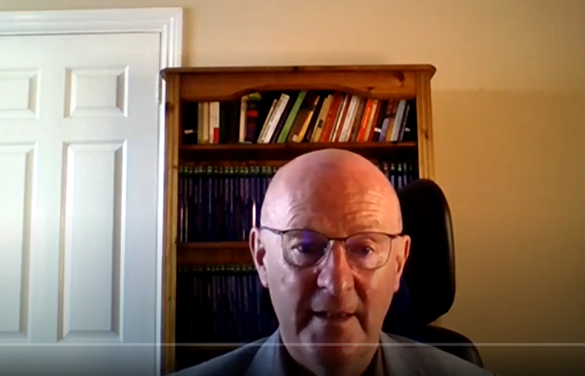 Dr Eamon Maher pictured in front of a white door and book shelf filled with books