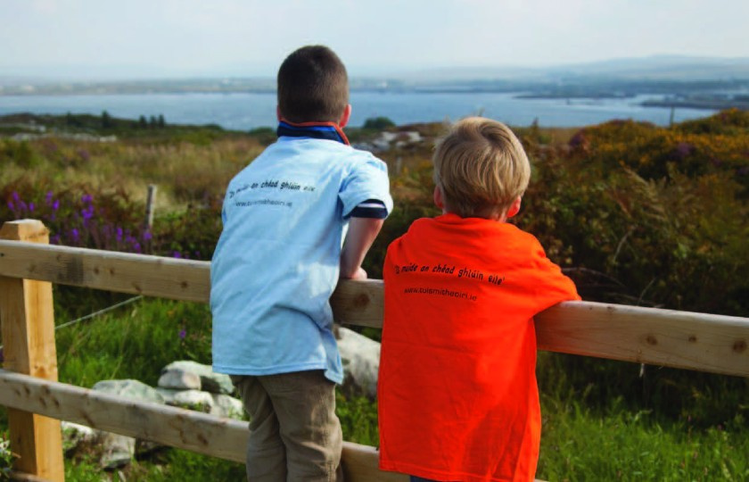Two boys looking out over green fields and a body of water
