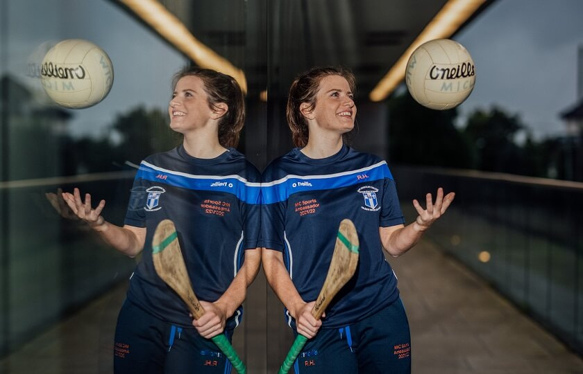 Róisín Howard, MIC Elite Sports Scholar 2021/22 holding a camogie stick and throwing a football