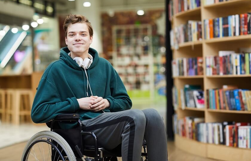 Young man in wheelchair in a library setting