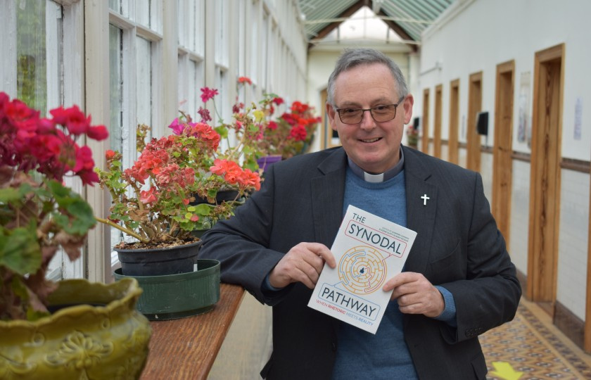 Professor Eamonn Conway in a corridor holding a copy of his book