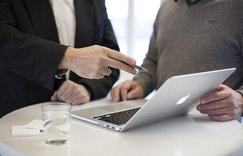 stock photo of two men around a laptop with one pointing to something on screen